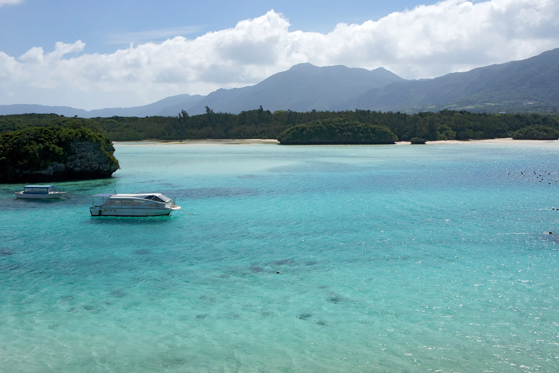 Bahía de Kabira en Ishigaki con agua turquesa, islotes verdes y barcas con fondo de cristal