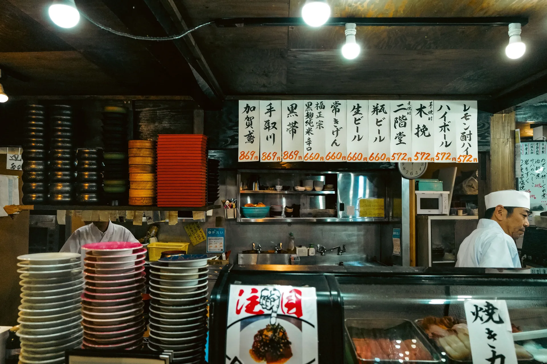 Cocinero detrás de la barra de un restaurante de sushi con la carta escrita en japonés