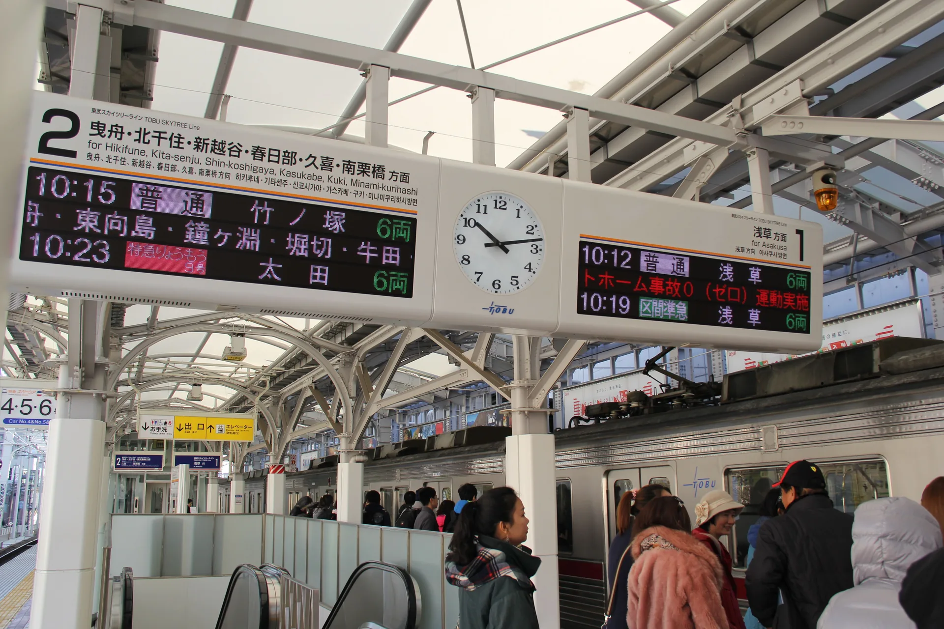 Panel de salidas con horarios y reloj en el andén de una estación de tren de Japón