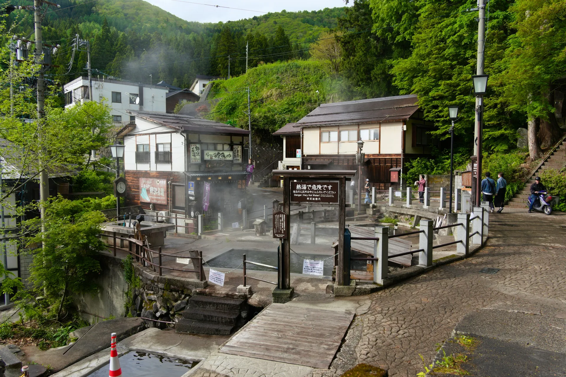 Onsen en Japón: qué es, cómo bañarse y dónde ir (guía completa) 2026 Calle del pueblo termal de Nozawa Onsen, en Nagano, con vapor saliendo de una fuente de agua caliente