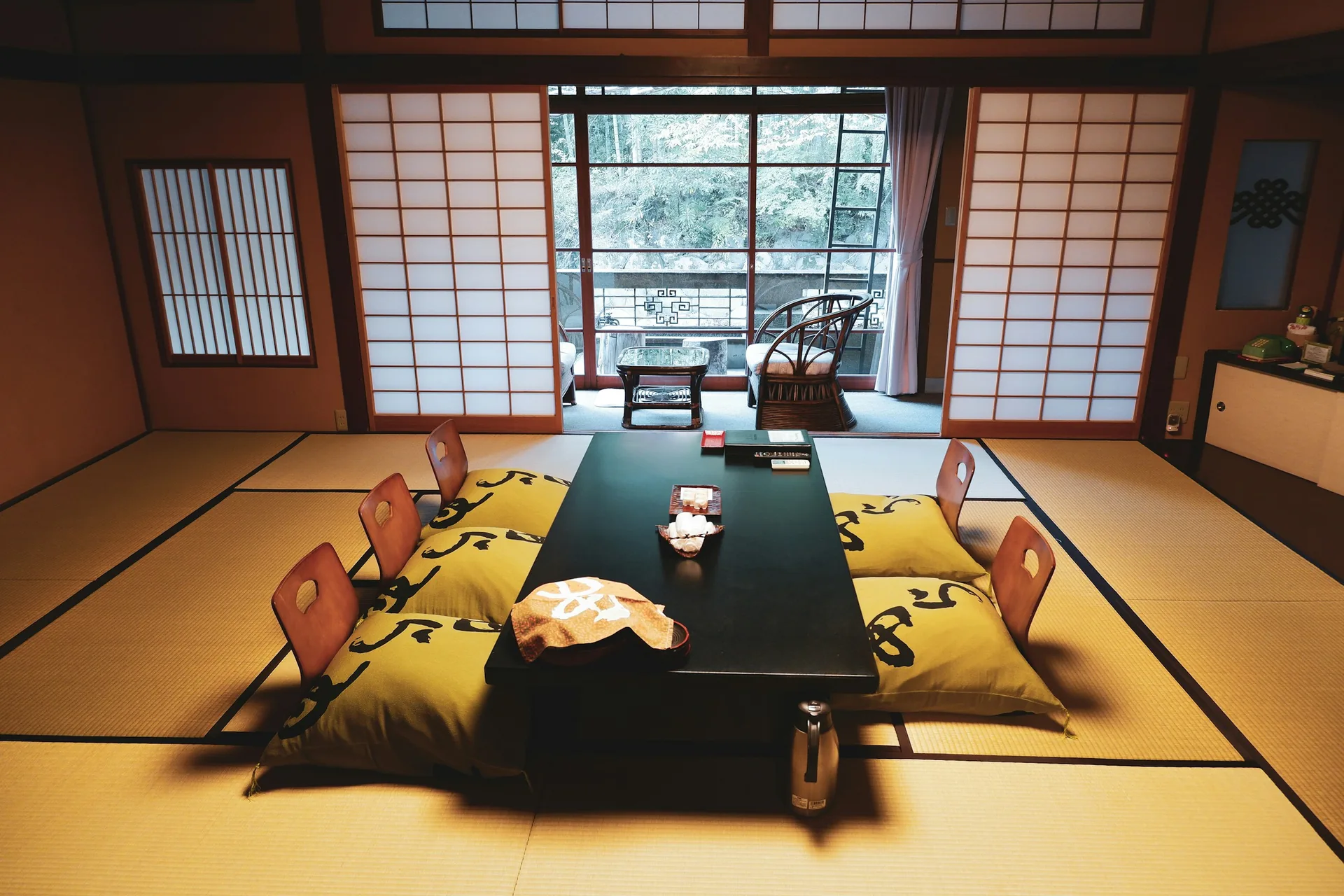 Habitación de un ryokan con suelo de tatami, mesa baja, cojines y sillas sin patas