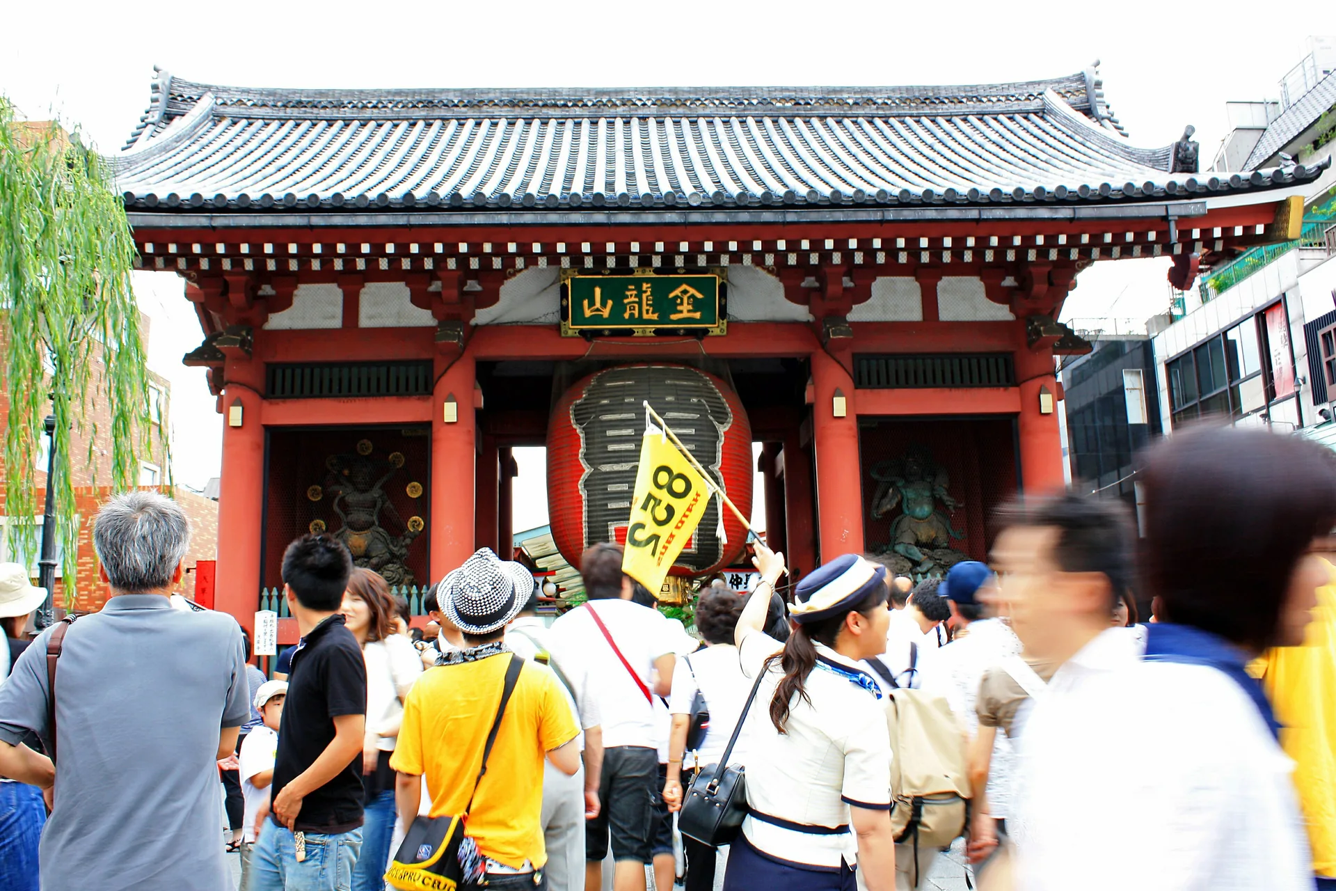 Grupo de turistas con guía y banderín ante la puerta Kaminarimon del templo Senso-ji, en Asakusa